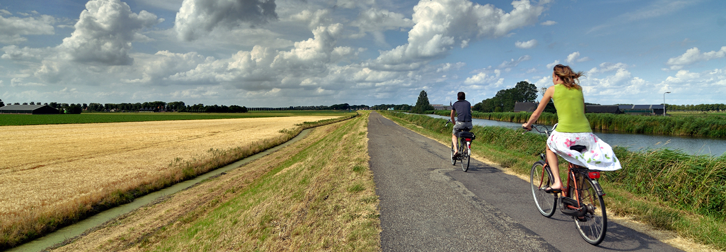 Twee fietsers die een Arthuur fietsroute fietsen lnags een kanaal.